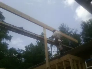 Carpenter setting a ridge beam over a new addition frame — Ice Dam Removal by Roofing Brothers in New Richland