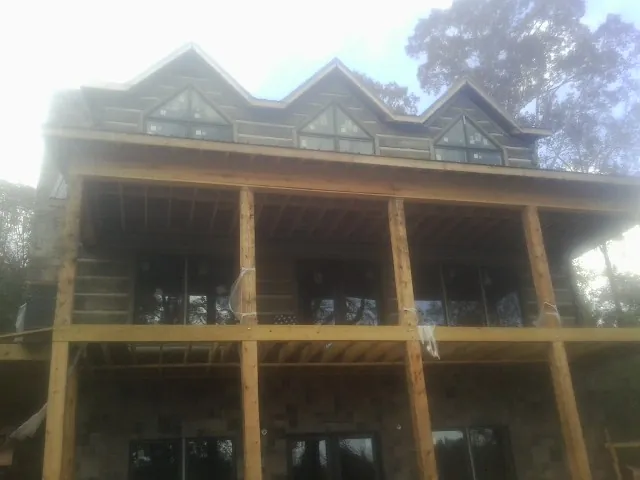 Dormers and porch framing on a large log home under construction — Roof Coating work by our crew in New Richland
