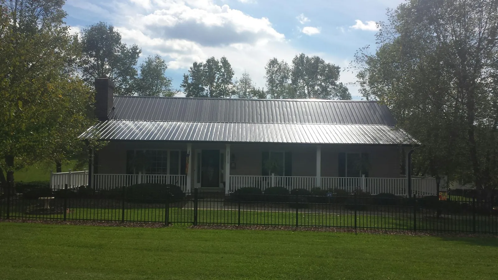 Gray metal roof on a brick ranch with a full width front porch — Gutter Guard Installation work by our crew in New Richland