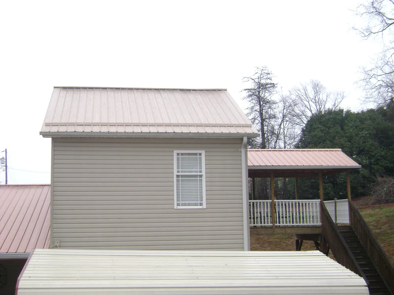Tan metal roofs on a two story addition and attached porch, from a Roof Replacement job in New Richland