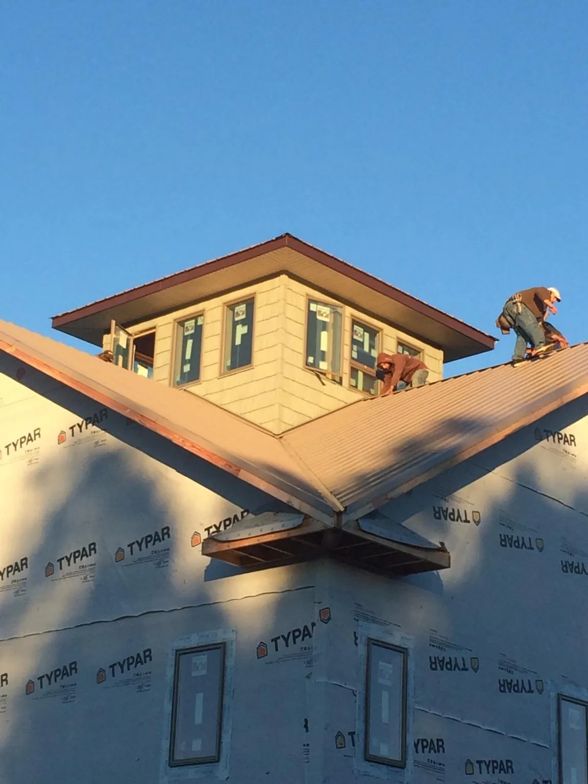 Roofers working around a rooftop cupola on a new metal roof at sunset — Roof Waterproofing in New Richland by Roofing Brothers